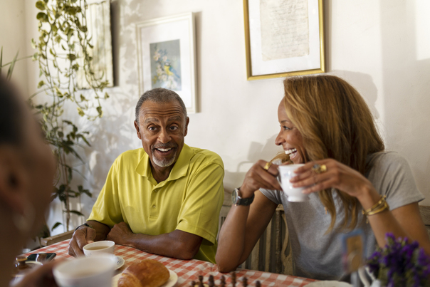 Personas adultas compartiendo café y sonrisas en una mesa